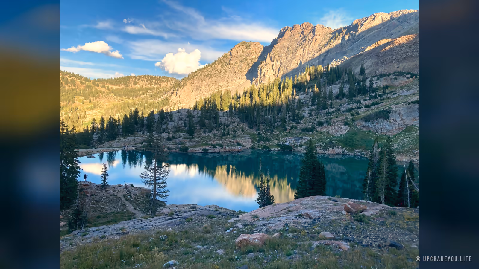 Cecret Lake, a teal alpine lake in the Utah mountains ringed by pines and rugged granite peaks under a clear sky