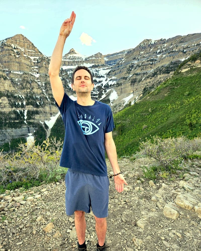 Jess con un braccio alzato sopra la testa in una postura di protezione, in alto su un crinale sotto il Monte Timpanogos.